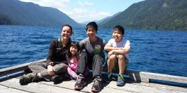 Wildlife Guide Carolyn poses with three young tour participants at the end of the Lake Crescent lodge dock with Lake Crescent and forested mountains in the background