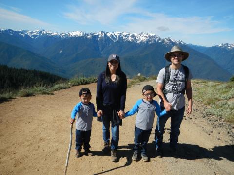 Hikers, including two young ones, pause for a photo as they ascent up the Hurricane Hill trail with the snowcapped Olympic Mountains in the background