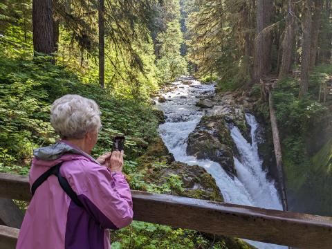 A hiker takes a photo from the bridge that crosses over the Sol Duc River just downstream from Sol Duc Falls in Olympic National Park