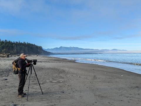 A hiker looks through a spotting scope from Dungness Spit on the Olympic Peninsula in Washington State
