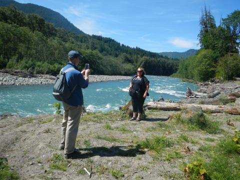 A tour participant poses next to the sparkling blue waters of the Elwha River