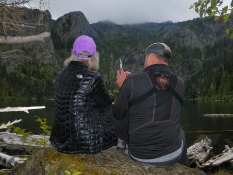 Two hikers sit for a moment at an overlook to Lake Angeles close to 4000 feet in elevation