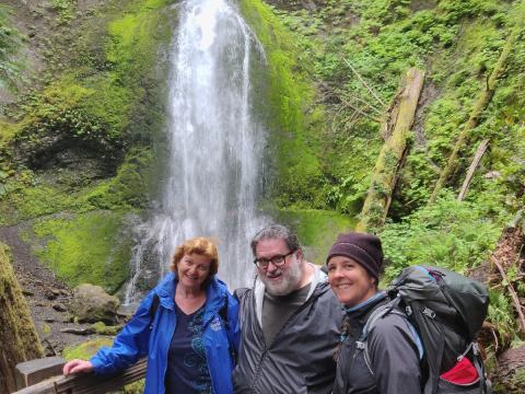 Hiking Guide Carolyn with two participants posting in front of Marymere Falls in Olympic National Park