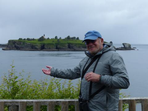 A tour participant poses on the last overlook on the Cape Flattery trail with Tatoosh Island in the background
