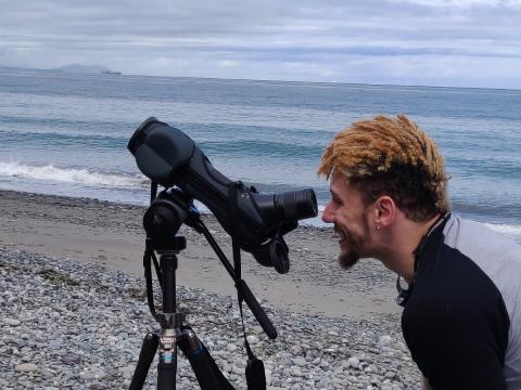 Hiker looks through spotting scope with the Pacific Ocean and Destruction Island in the background